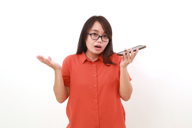 困惑的年轻亚洲女子站着用扩音器打电话图片下载