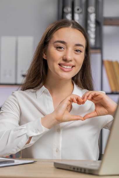 高加索女商人制作爱心符号，对着镜头表达浪漫情怀图片下载