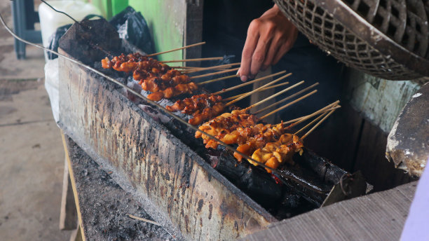 一名印尼男子在木炭和烟熏上烤沙爹鸡，看起来很开胃。图片下载