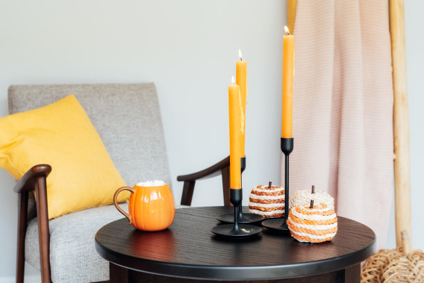 秋天舒适的心情构成了hygge家居装饰。一杯有棉花糖的热饮，柳条南瓜，咖啡桌上点着的蜡烛，客厅里有靠垫的现代扶手椅。秋天内部图片下载