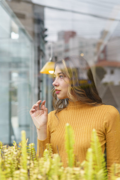 女人用长发和红唇化妆，用举起的手遮住橱窗，美丽又时尚图片下载
