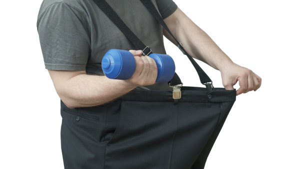 这名男子脱掉腰部的裤子，举起哑铃。图片下载