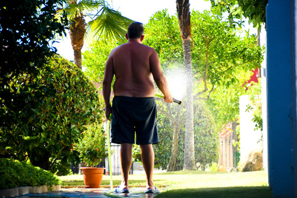 一个人用水管给花园浇水图片下载