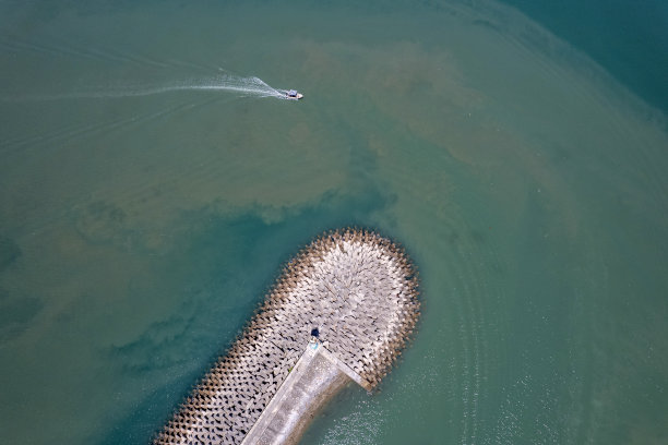 一艘船驶离渔港大坝的鸟瞰图图片下载