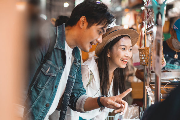 一对来自亚洲的背包客夫妇在泰国曼谷Yaowarat路的夜市与人群一起享受和吃街头小吃。图片下载