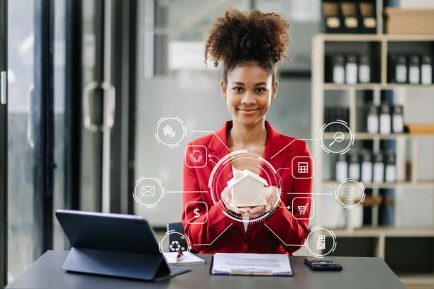 年轻的房地产中介工作人员在办公室的桌子上放着笔记本电脑和平板电脑，旁边是小房子。图片下载