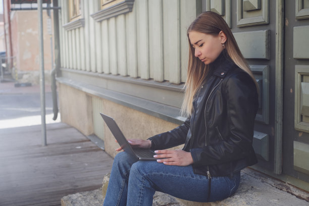一个漂亮的金发白人女孩，穿着黑色夹克和蓝色牛仔裤图片下载