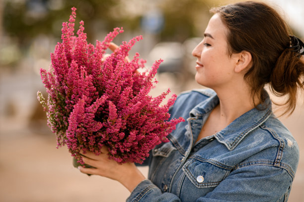 迷人的女人手里拿着花盆，花盆里有开花的石南花图片下载