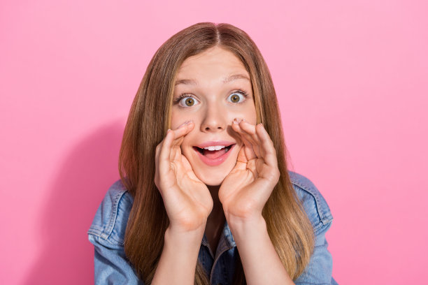 迷人的年轻少女的照片肖像闭上嘴分享秘密穿着时尚的牛仔服装孤立的粉红色背景图片下载