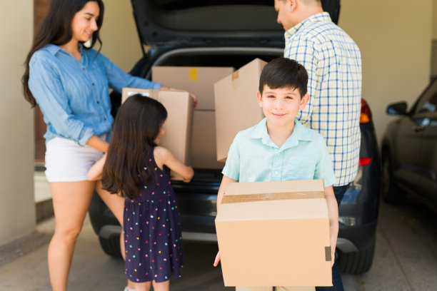 西班牙裔孩子搬到新房子时从车上搬箱子图片下载