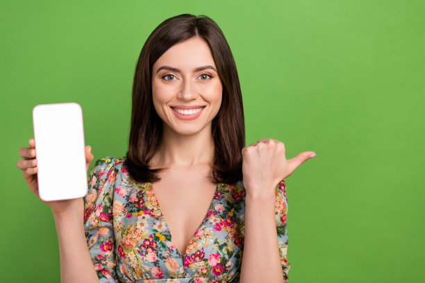 迷人的积极女士的照片展示空白空间智能手机显示直接手指提供孤立的绿色背景图片下载
