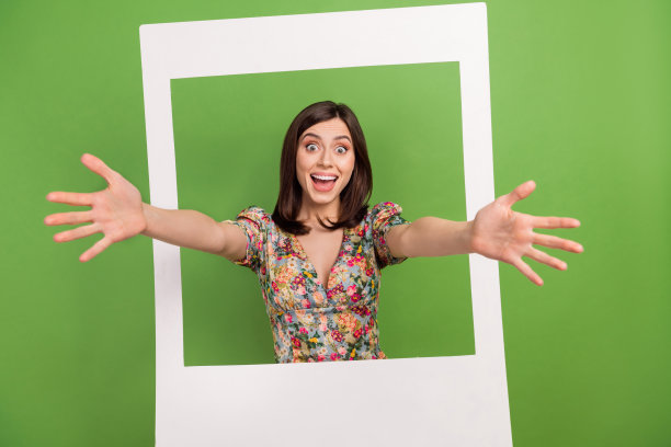 开朗友好的人的肖像，通过孤立的绿色背景的纸质相册卡举起双臂图片下载