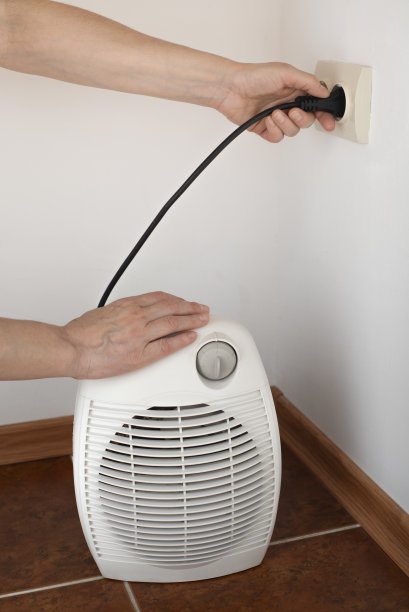 女手将空间风扇加热器插入墙壁电源插座图片下载