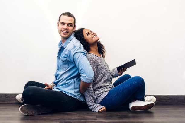 两个朋友一起放松地使用智能手机的技术，查看墙壁背景上的社交应用。沟通的概念图片下载