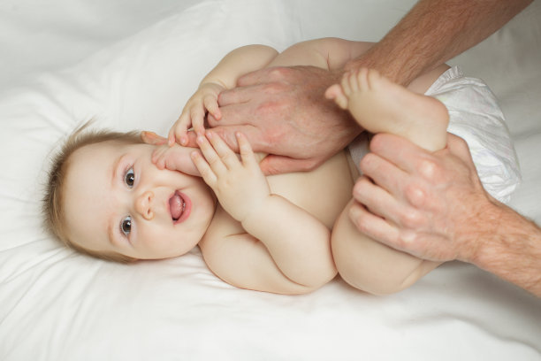 可爱快乐的7个月女婴穿着尿布躺着玩耍图片下载