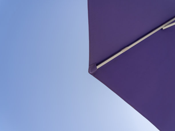 紫色的遮阳伞。蓝色的天空作为背景。视图从下面。放松的环境。在海边过暑假。一般比赛和地点图片下载