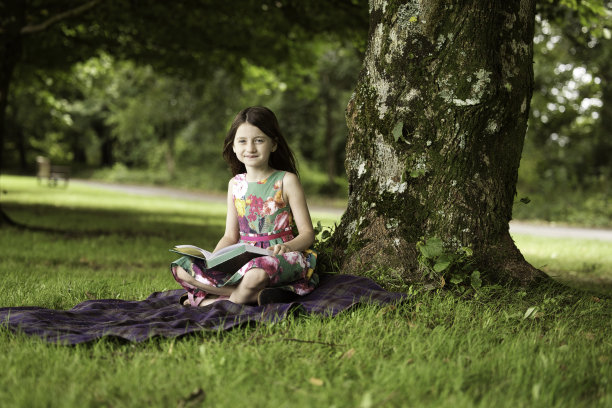 六岁的小女孩在公园里看书图片下载