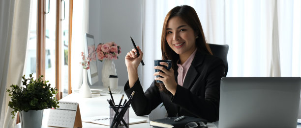 华丽的亚洲女商人喝热咖啡或茶，享受她的闲暇时间在她的工作休息。图片下载