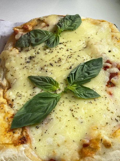 玛格丽塔披萨的特写图片，白色盘子上装饰着罗勒叶，融化的金色水牛马苏里拉奶酪和丰富的番茄马里纳拉酱浇头图片下载