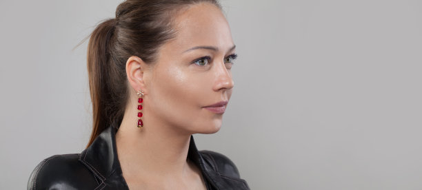 迷人的女人戴着金色的珠宝耳环与红色的石头在灰色的横幅背景图片下载