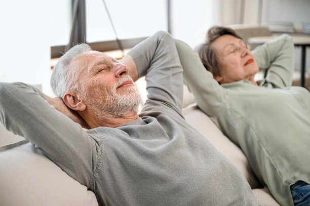 无忧无虑的老夫妇在家里的沙发上放松图片下载