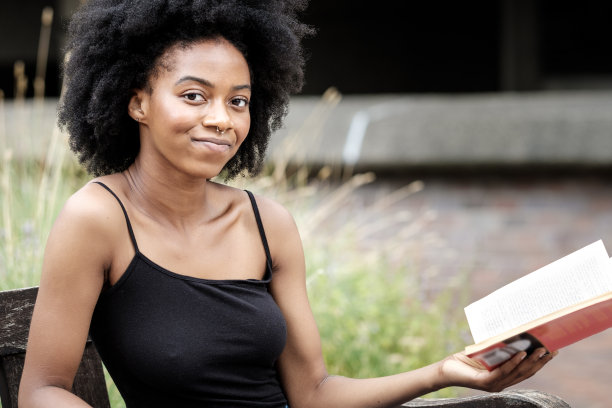 微笑的女人拿着一本书看着镜头。图片下载