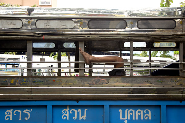 在泰国曼谷，一只脚从一辆公交车的窗户伸出来。图片下载