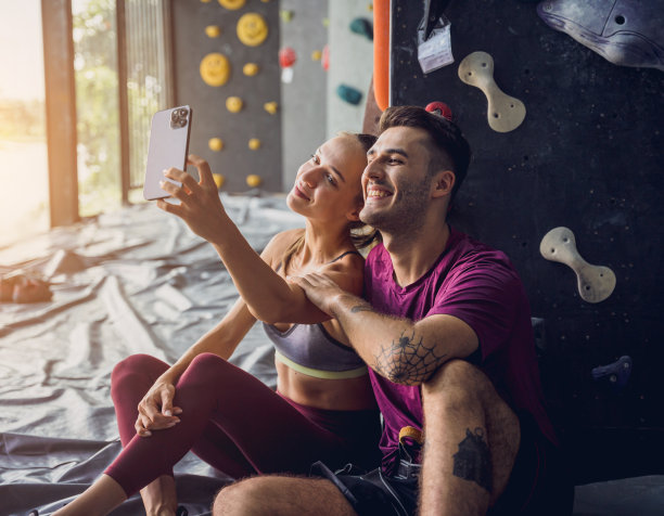 一对强壮的攀登者用彩色的握把和绳索顶着一堵人造墙。图片下载