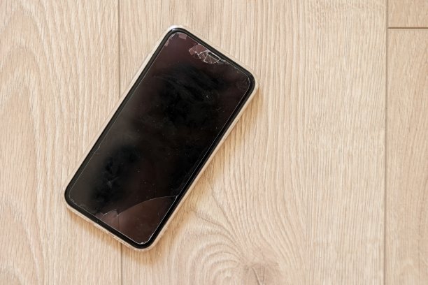 触屏坏掉的智能手机，木质背景上有裂缝的玻璃。手机显示裂缝模型。手机撞到，撞坏，刮伤。设备被毁。电子设备维修图片下载