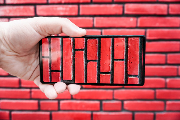 剪短的手拿着手机在建筑物前图片下载