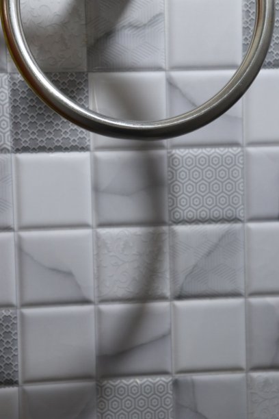 白色瓷砖墙上的银色钢制圆形毛巾架特写图片下载