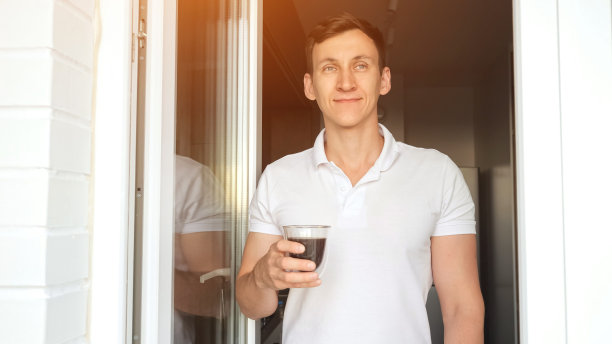 积极的男人站在阳台上喝咖啡图片下载