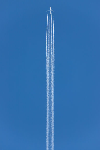 在高空飞行的四引擎商用飞机后面的发动机排气尾迹图片下载
