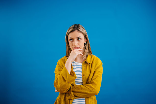 站在蓝色背景下沉思的年轻女子图片下载