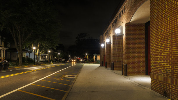 晚上空荡荡的街道上的消防大楼。沿路有弧形和入口的照明砖制公共建筑。W Reed St，多佛尔市中心，DE。图片下载