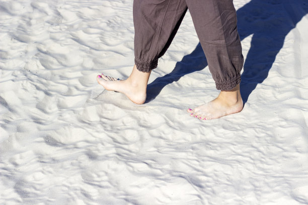 走在沙滩上，走在沙漠里，腿在白沙上特写图片下载