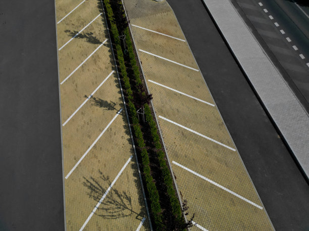 对角线停车。无人机拍摄的购物中心停车场，中间有小巷。黄色、棕色、沙子、瓷砖比混凝土更赏心悦目。路行图片下载