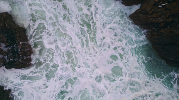 泡沫般的海水在海岸岩石间冒泡。空中惊涛骇浪图片下载