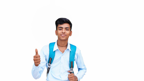 一个穿着双肩包的男生，在孤立的白色背景下，用拇指指着一边，脸上带着快乐的微笑图片下载