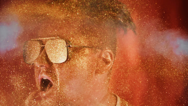 勇敢的人把闪光的微粒洒在自己身上。魅力奢华的照片，闪亮的脸，张开的嘴。富观肖像男人们戴着墨镜，脸上洒满了金色的光芒。图片下载