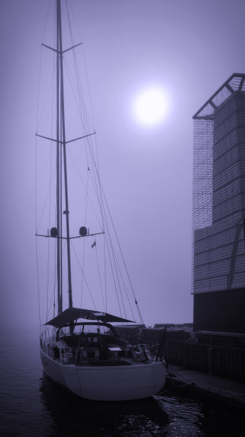 加拿大新斯科舍省，哈利法克斯港雾蒙蒙的早晨，一艘停泊的船和冉冉升起的太阳，蓝色调的高画幅照片，用于手机背景图片下载