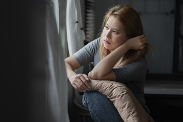 一个沮丧的女人坐在大窗边，脸上带着悲伤的表情图片下载