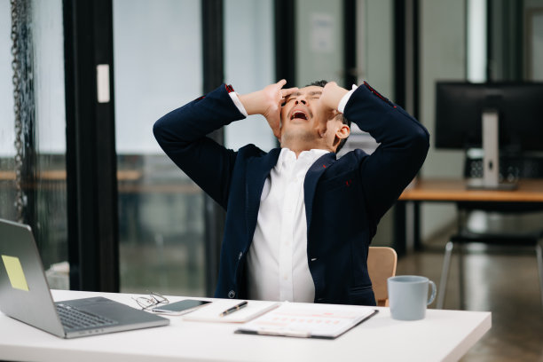 劳累过度的年轻亚洲商人办公室职员在办公桌前工作了一整天后颈部疼痛。办公室综合症概念图片下载