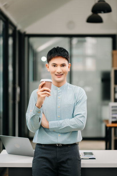 年轻有魅力的亚洲男性办公室职员在办公室对着镜头微笑图片下载