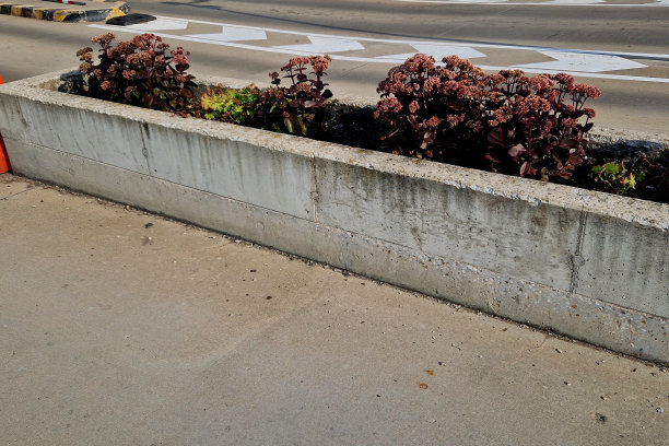 露台上的停车场有两个灰色的花盆，人造草坪让人想起。花盆里有草和紫色的花。餐厅附近的温泉公园图片下载