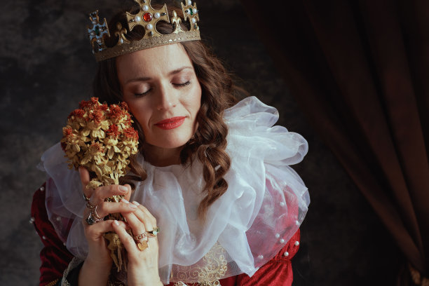 放松的中世纪女王穿着红色礼服和干花图片下载