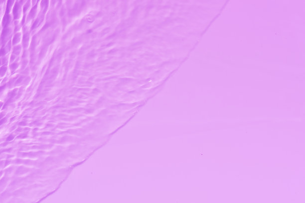 紫色的水面上泛起涟漪。散焦模糊透明粉红色透明平静水面纹理与飞溅和泡沫。水波与闪亮的图案纹理背景。图片下载