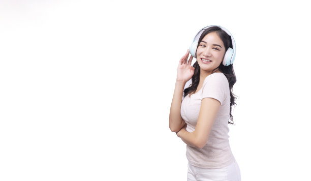 快乐的亚洲妇女使用无线耳机享受听收音机音乐在孤立的白色背景。美丽的年轻女士戴着耳机，听着白色背景的数字音乐。图片下载