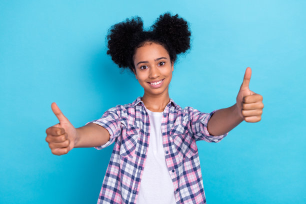 自信漂亮的女士穿着格子衬衫的照片，显示你两个大拇指向上孤立的蓝色背景图片下载