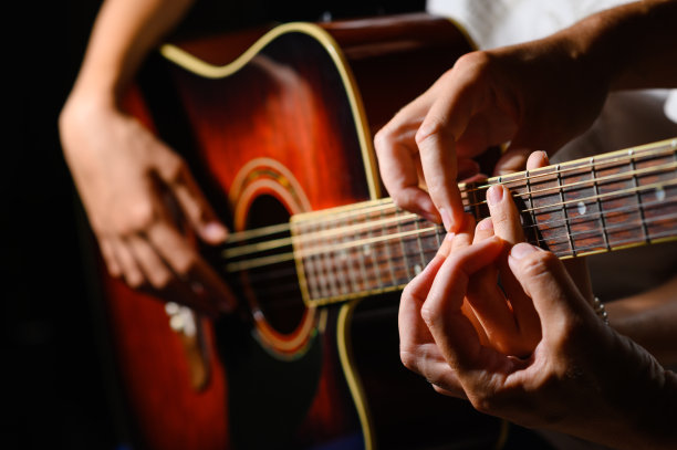 学习弹吉他的特写。老师的手向学生展示如何用手在吉他指板上工作。选择性地关注手部。图片下载